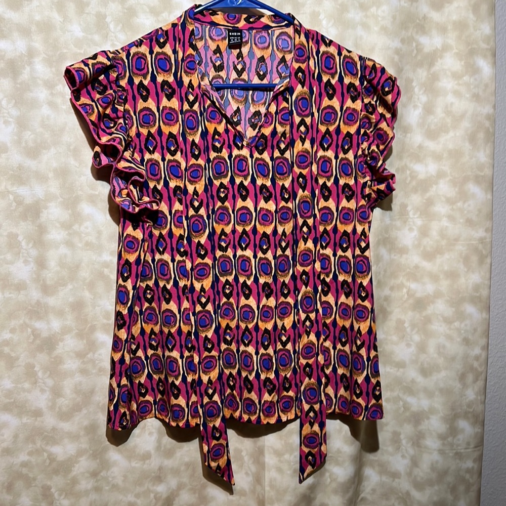 All over print , ruffle trim tee. With flowing tie attached  at the neck.